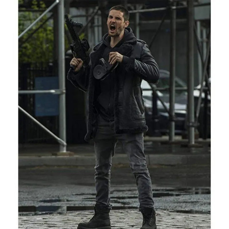 A man in a wet urban setting wearing a black leather jacket, black hoodie, dark gray jeans, and black boots, holding a rifle and shouting.