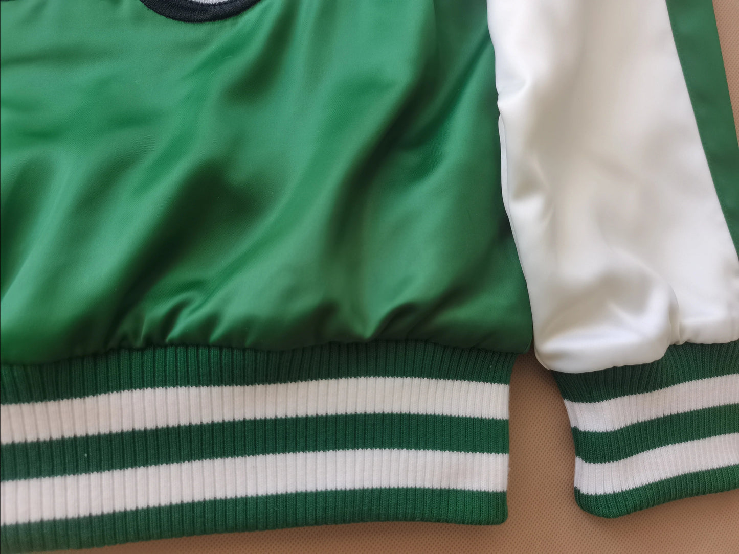 Close-up of green and white jacket with striped cuffs on a brown surface