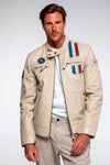 Man wearing a beige jacket with patches on a plain background