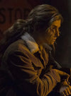 Person wearing a brown coat with fur lining in a dimly lit setting