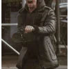 Person wearing a dark coat with a hood, standing outdoors.