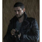 A man in a dark, wet black coat with a high collar, holding a camera in a rainy, dramatic scene.