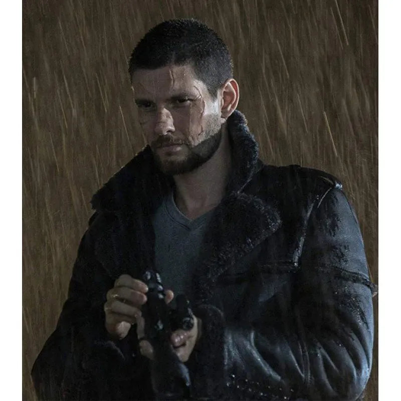 A man in a dark, wet black coat with a high collar, holding a camera in a rainy, dramatic scene.