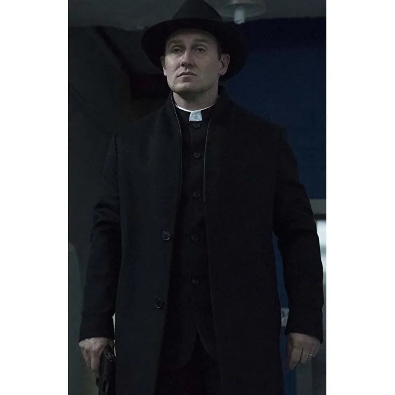 Man in a dark coat and hat standing indoors