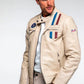 Man wearing a beige jacket with patches on a light gray background