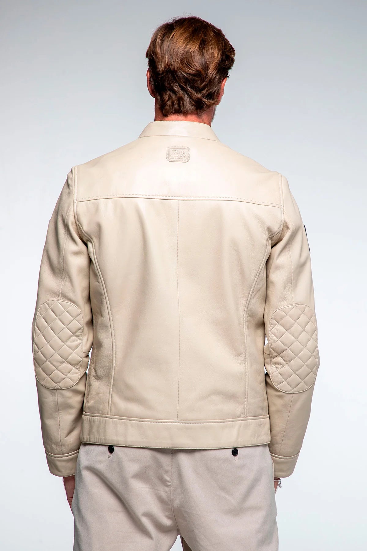 Man wearing a beige quilted jacket on a plain background