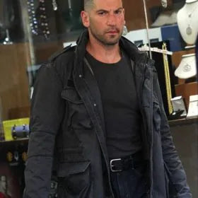 Man wearing a dark jacket and black shirt in an indoor setting