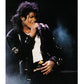 Person in a black leather jacket with a microphone, performing on stage.