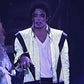 Person in a white jacket with black accents on a dark background
