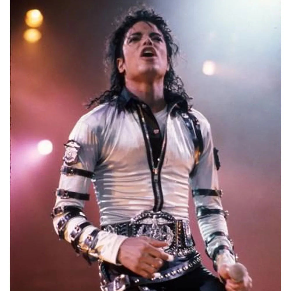 Person in a white outfit with black accents, performing on stage.
