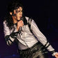 Person in a white shirt and black leather outfit holding a microphone on a dark background