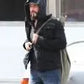 Person wearing a black jacket and blue jeans with a backpack, standing outdoors.