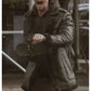 Person wearing a dark coat with a hood, standing outdoors.
