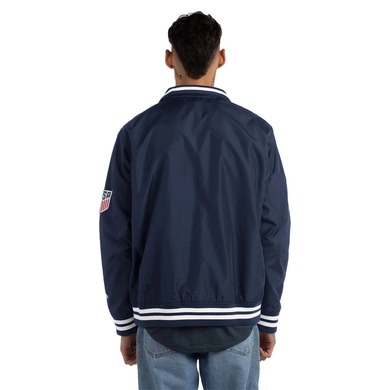 Person wearing a navy blue jacket with a logo on the sleeve against a white background