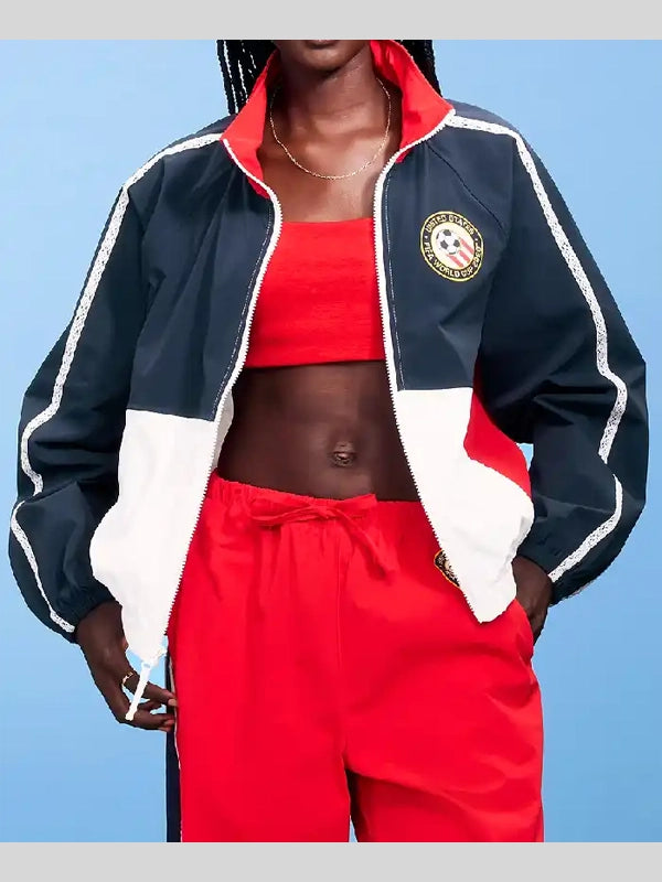 Person wearing a navy, red, and white tracksuit with a blue background