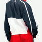 Person wearing a navy, white, and red tracksuit on a white background