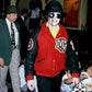 Person wearing a red and black jacket with 'Navy' logo, surrounded by people in a social setting.