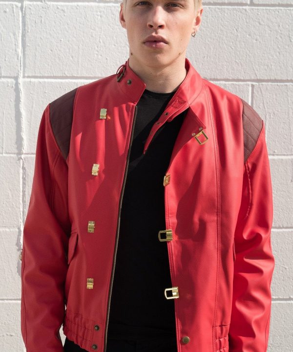 Person wearing a red jacket with gold accents against a gray brick wall.