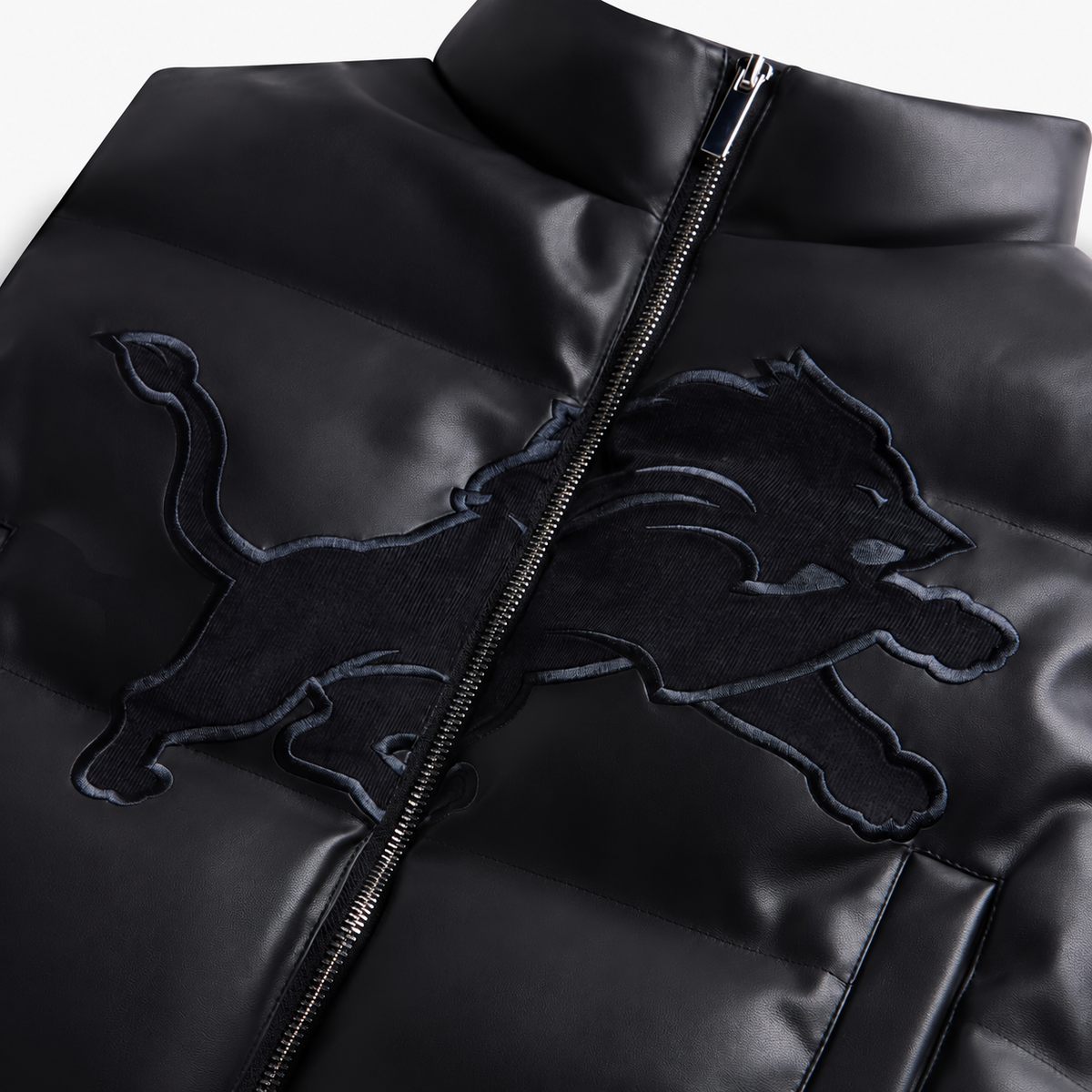 Close-up of Detroit Lions design and zipper on black faux leather cropped puffer vest
