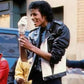 Person in a leather jacket holding an ice cream cone outdoors